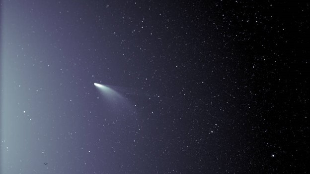An unprocessed image from the WISPR instrument on board NASA’s Parker Solar Probe shows comet NEOWISE on July 5, 2020, shortly after its closest approach to the Sun. The Sun is out of frame to the left. The faint grid pattern near the center of the image is an artifact of the way the image is created. The small black structure near the lower left of the image is caused by a grain of dust resting on the imager’s lens. Credits: NASA/Johns Hopkins APL/Naval Research Lab/Parker Solar Probe/Brendan Gallagher